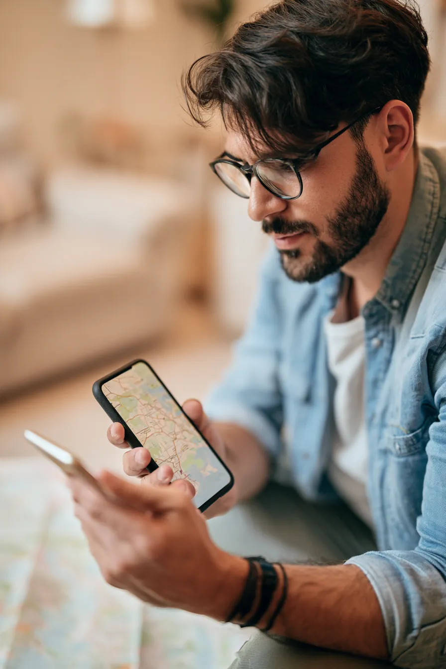 Man planning a vacation itinerary while holding a phone displaying a travel route map